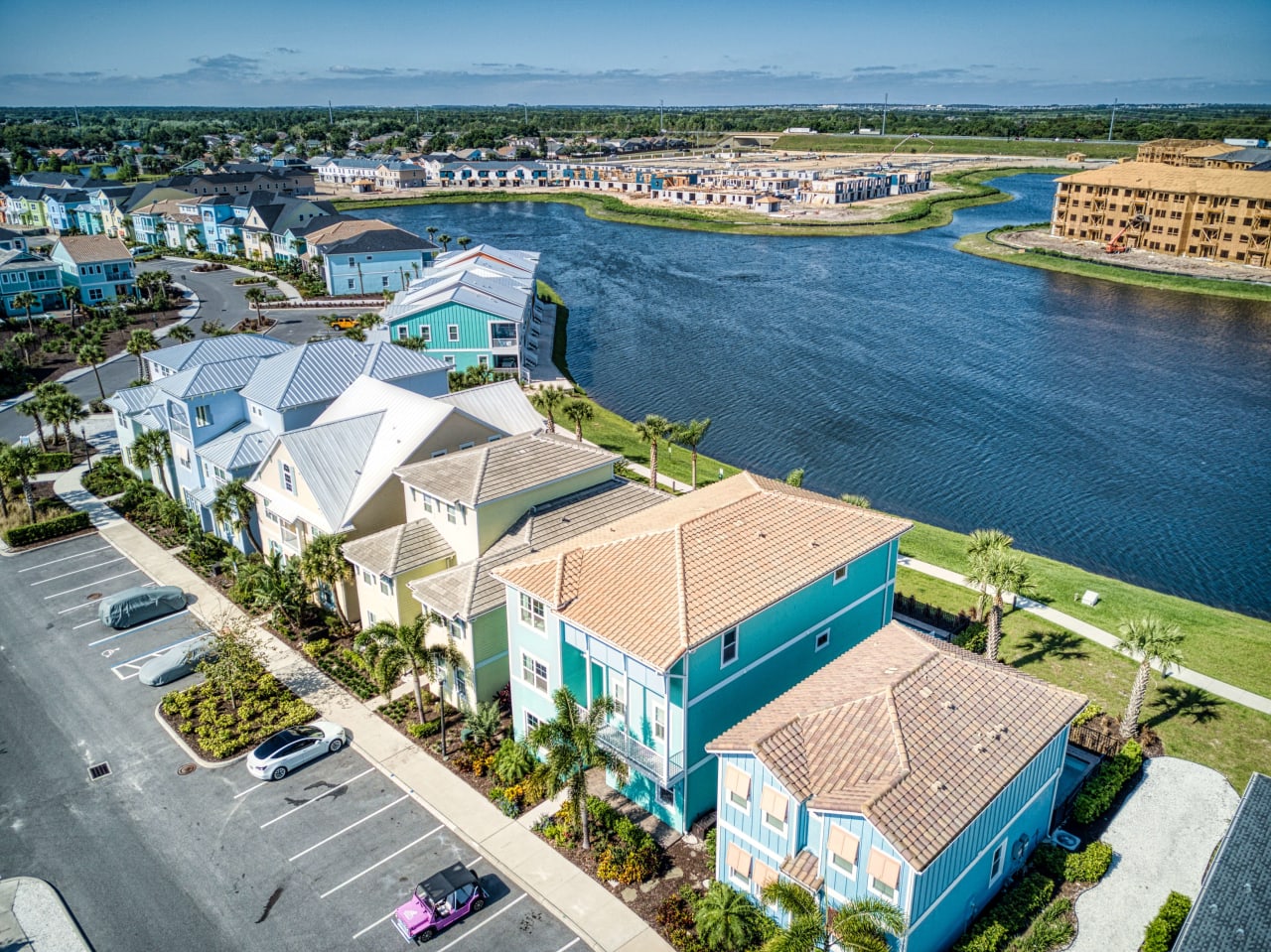 A bird's-eye view of a neighborhood with houses in various colors and sparkling blue lake is visible in the background.