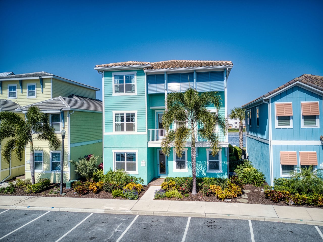 A row of brightly colored houses with palm trees in front of them.