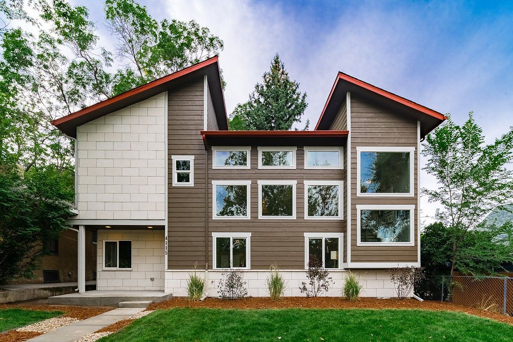  A striking modern two-story house with a symmetrical design, featuring a combination of dark brown horizontal siding and light-colored square paneling, accented by white window frames.