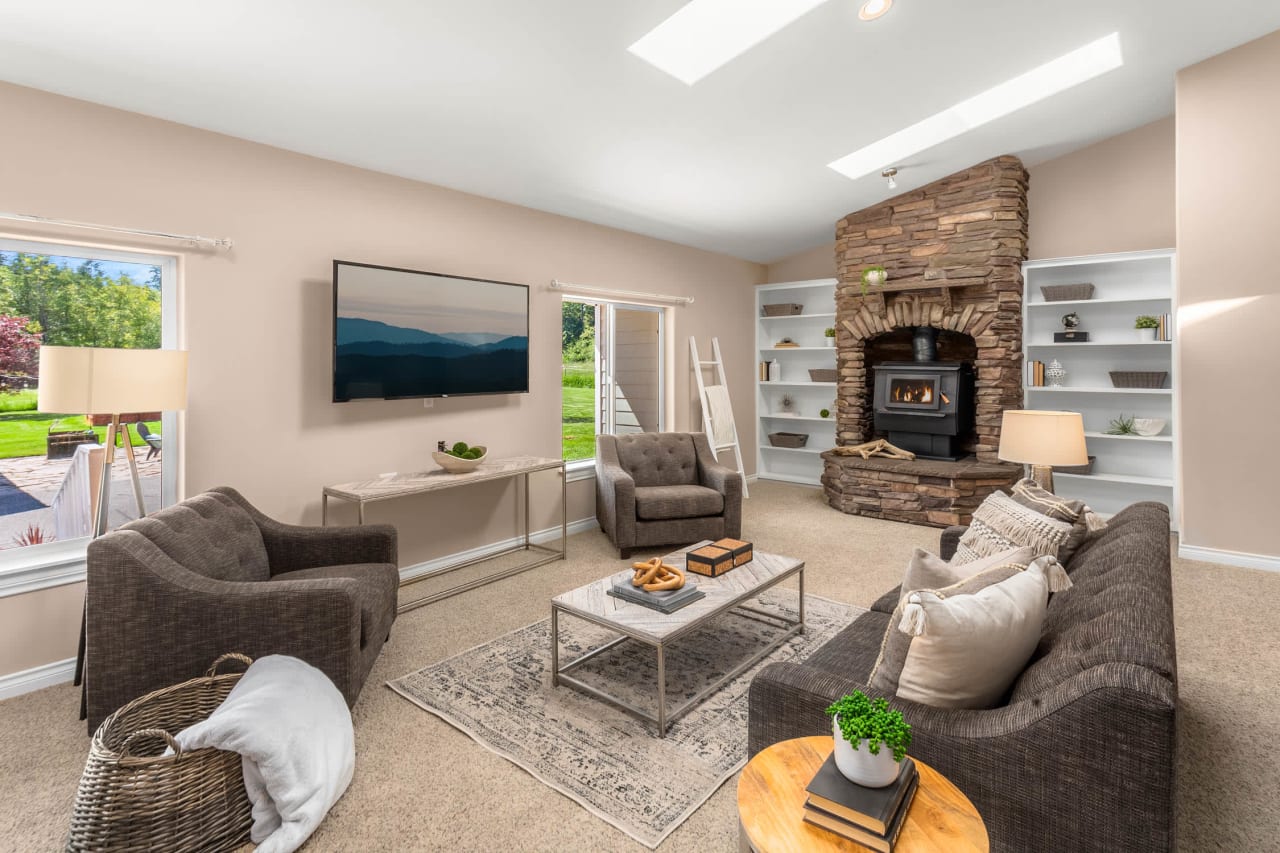 A cozy living room with a stone fireplace, a flat-screen TV