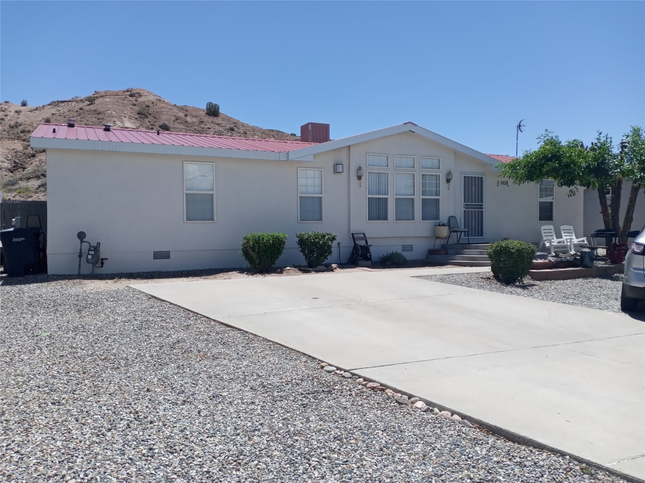 A mobile home with a red roof and a gravel driveway.