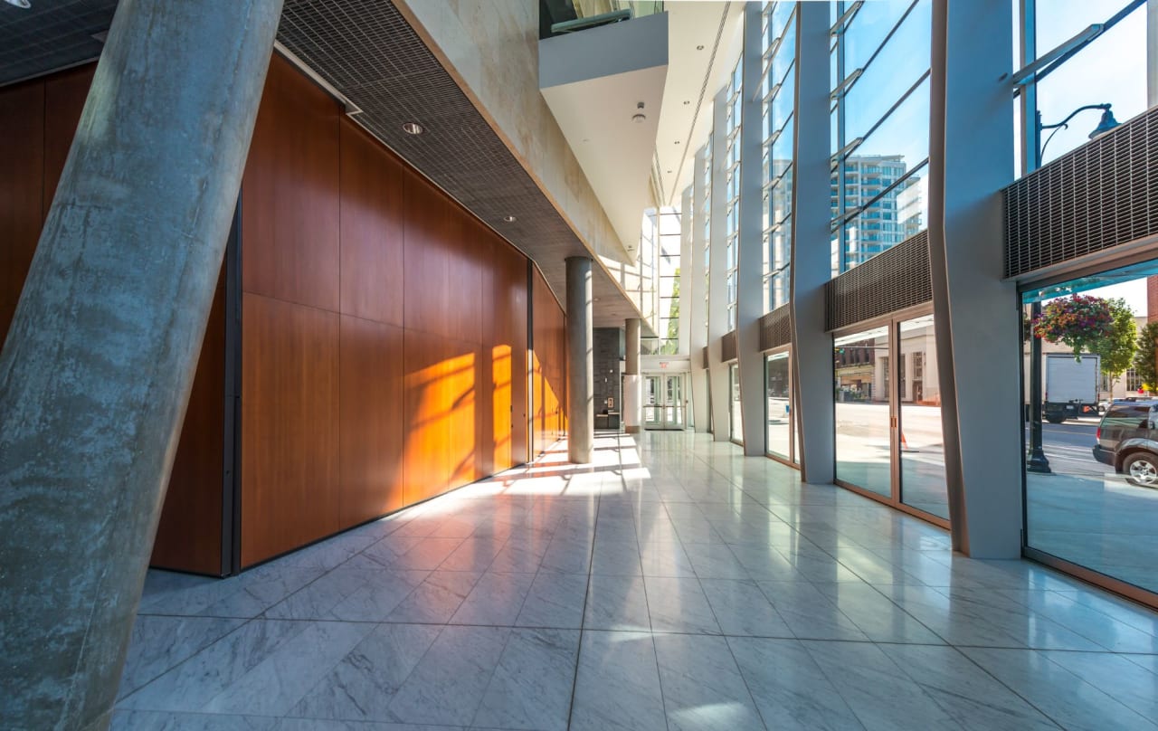 A long, sunlit hallway with large windows and marble floors on a bright sunny day.