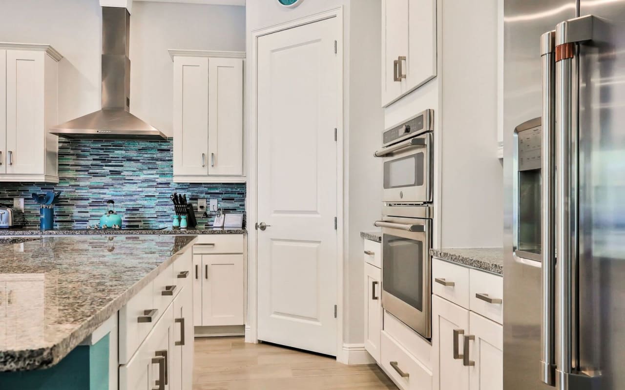 A modern kitchen with white cabinets and stainless steel appliances.