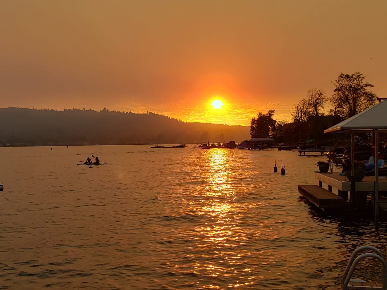 A couple of people kayaking on a lake at sunset