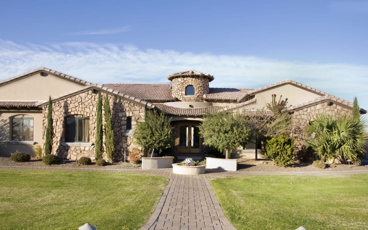 A large house with a stone facade and a brick walkway leading up to the front door.