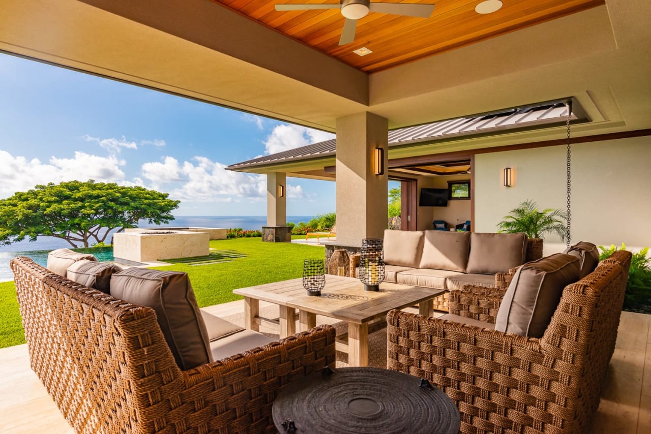 A patio with a modern seating area and a view of a tranquil backyard