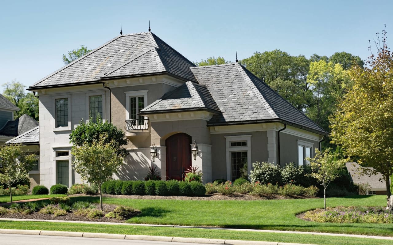 A large house with a slate roof in a residential neighborhood. 