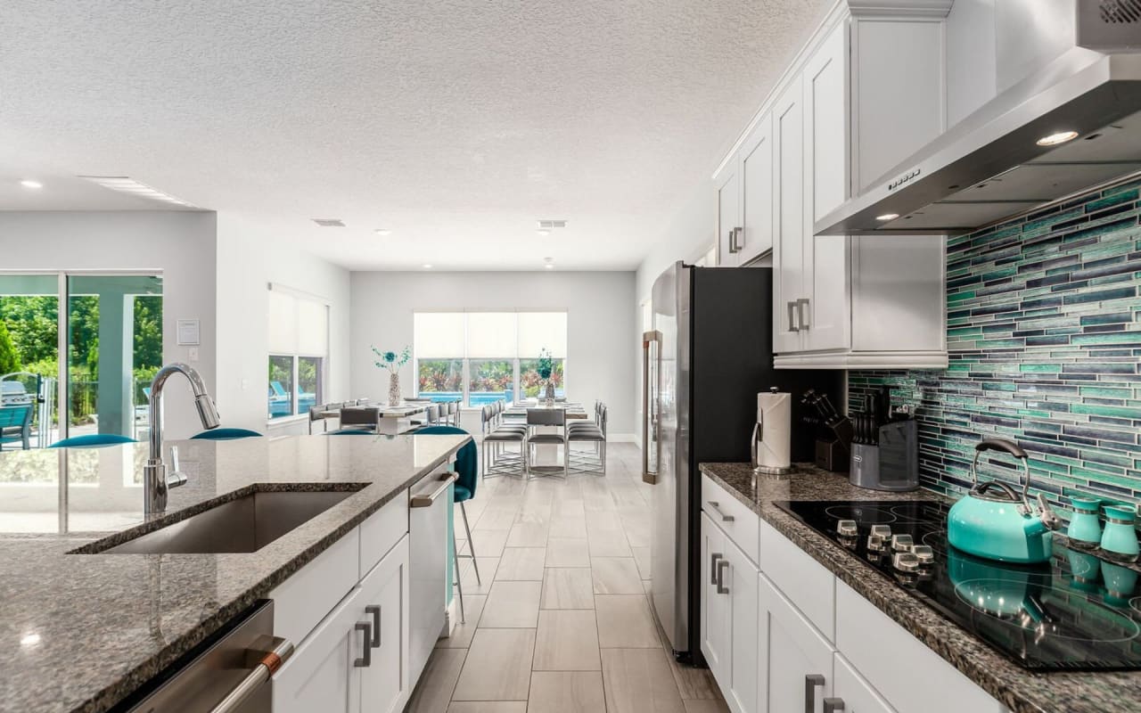 A well-lit kitchen with a stainless steel sink and refrigerator.