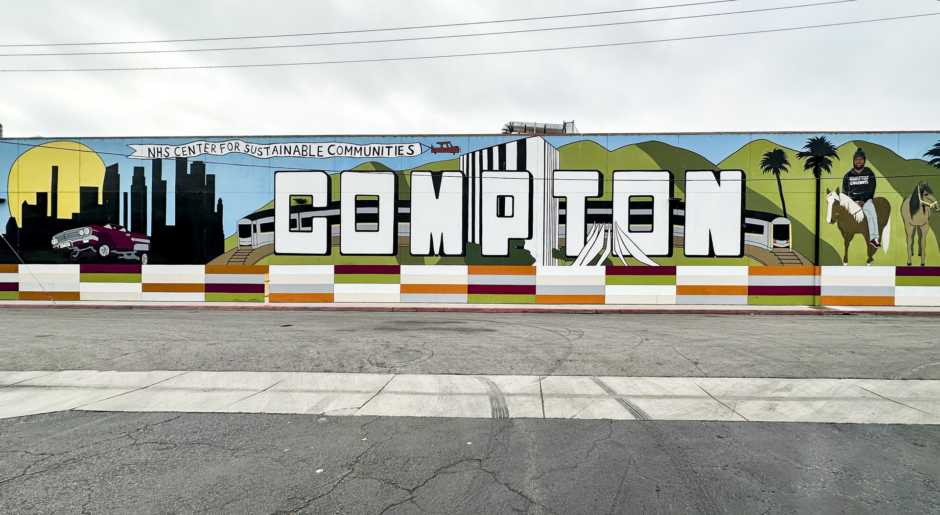 Compton lettering mural at the NHS Center for Sustainable Communities, with a horseback rider and lowrider painted in the letters
