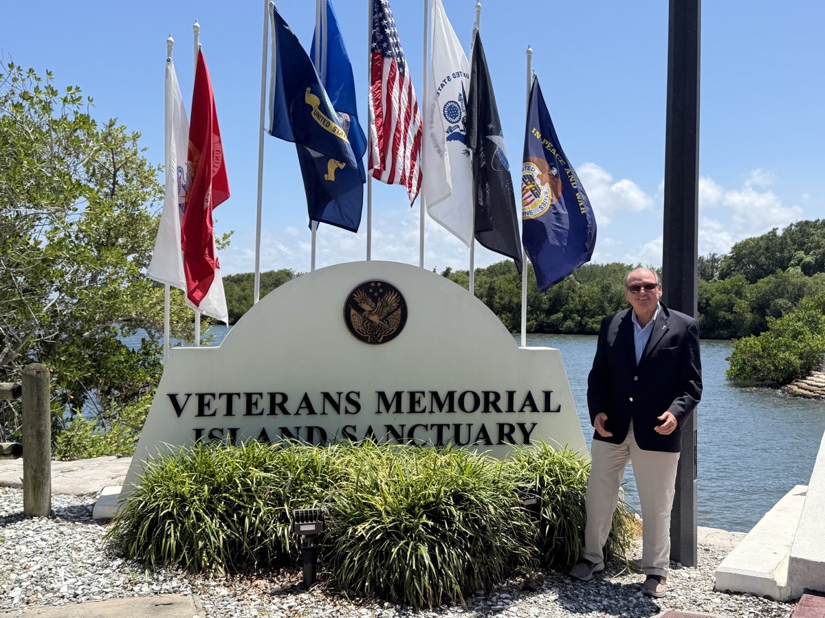 J. Vance Brinkerhoff at the Veterans Memorial Island Sanctuary in Vero Beach, Florida, with the American flag and armed-forces flags along the Indian River Lagoon