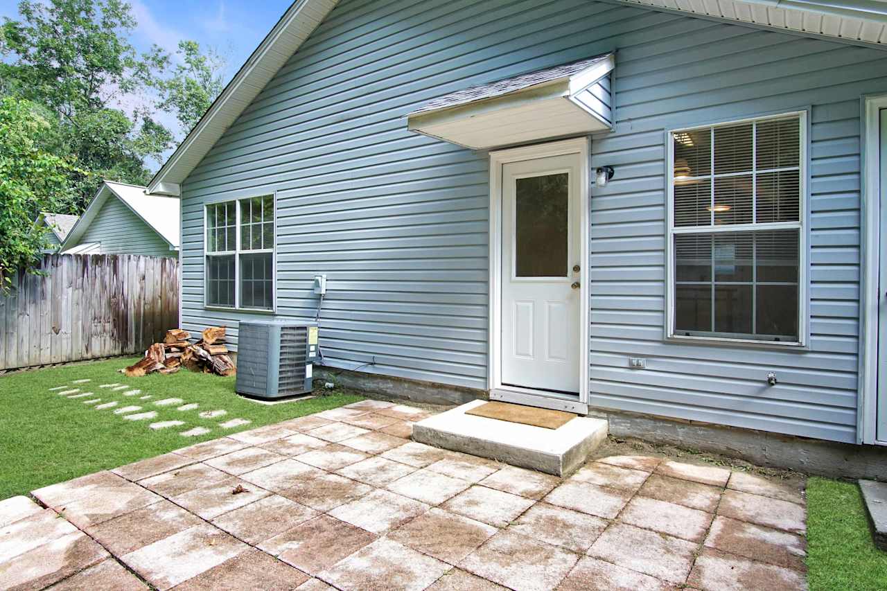 photo of pavered back patio featuring half window back door, fenced yard, HVAC unit, outdoor storage closet, and stone pathway to patio at 2709 Oak Park Court, Tallahassee, Florida 32308 at 2709 Oak Park Court, Tallahassee, Florida 32308