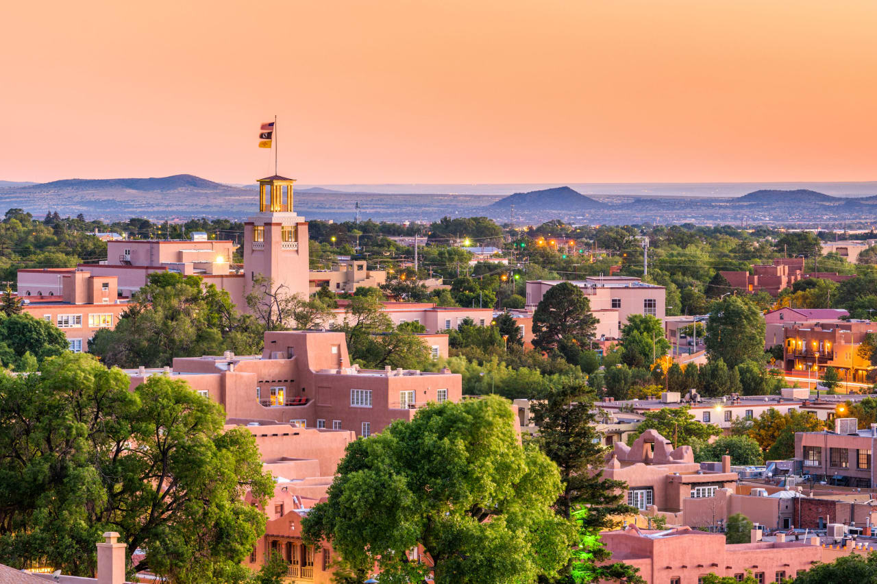 An aerial view of a city at sunset with a clock tower in the center.