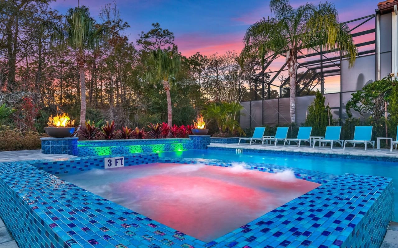 A large rectangular swimming pool with a round hot tub next to it.