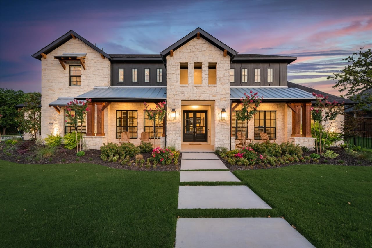 A large house with a walkway, tree, and garage