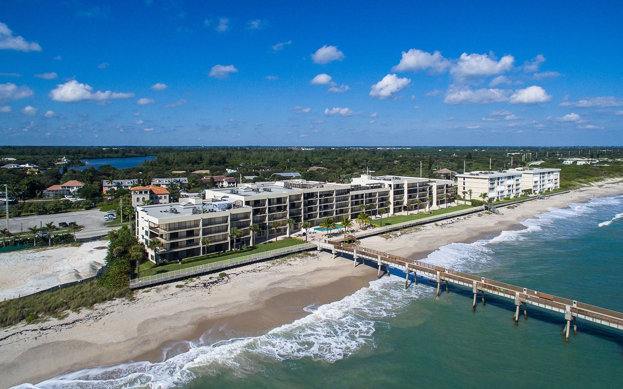 Aerial drone photograph of oceanfront condominiums and a fishing pier on the Vero Beach barrier island, Florida