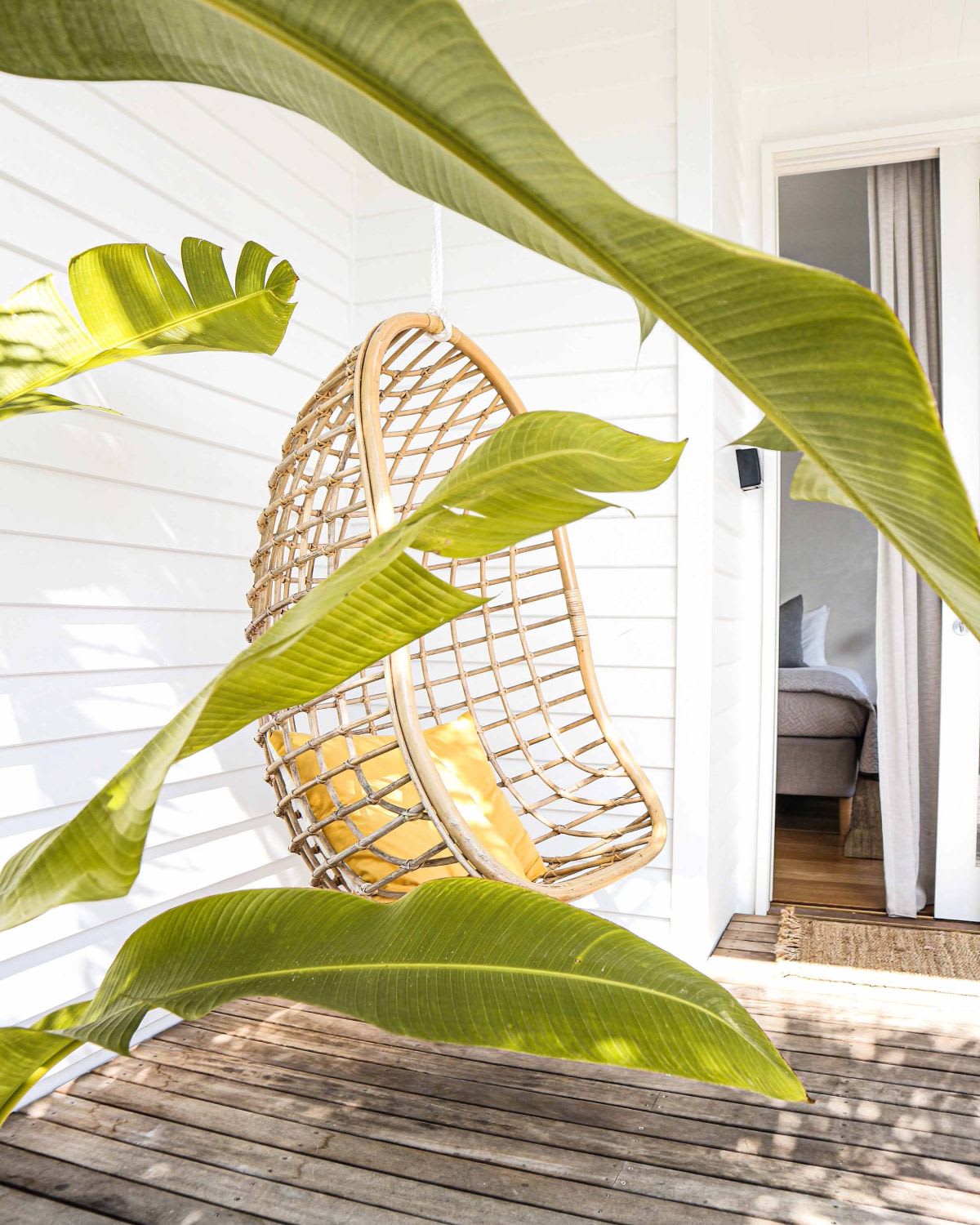 A cozy hanging chair with a yellow pillow.