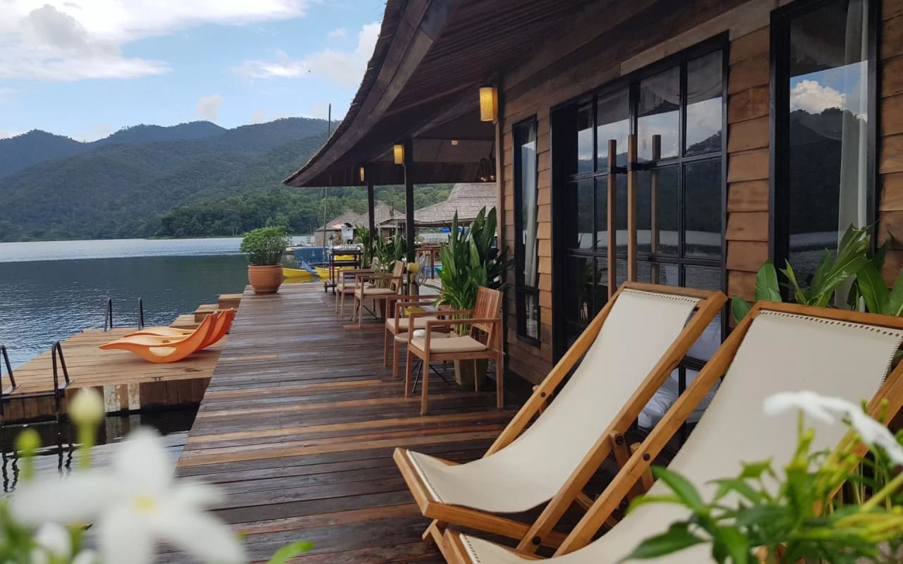 A wooden deck with chairs and tables overlooking a lake