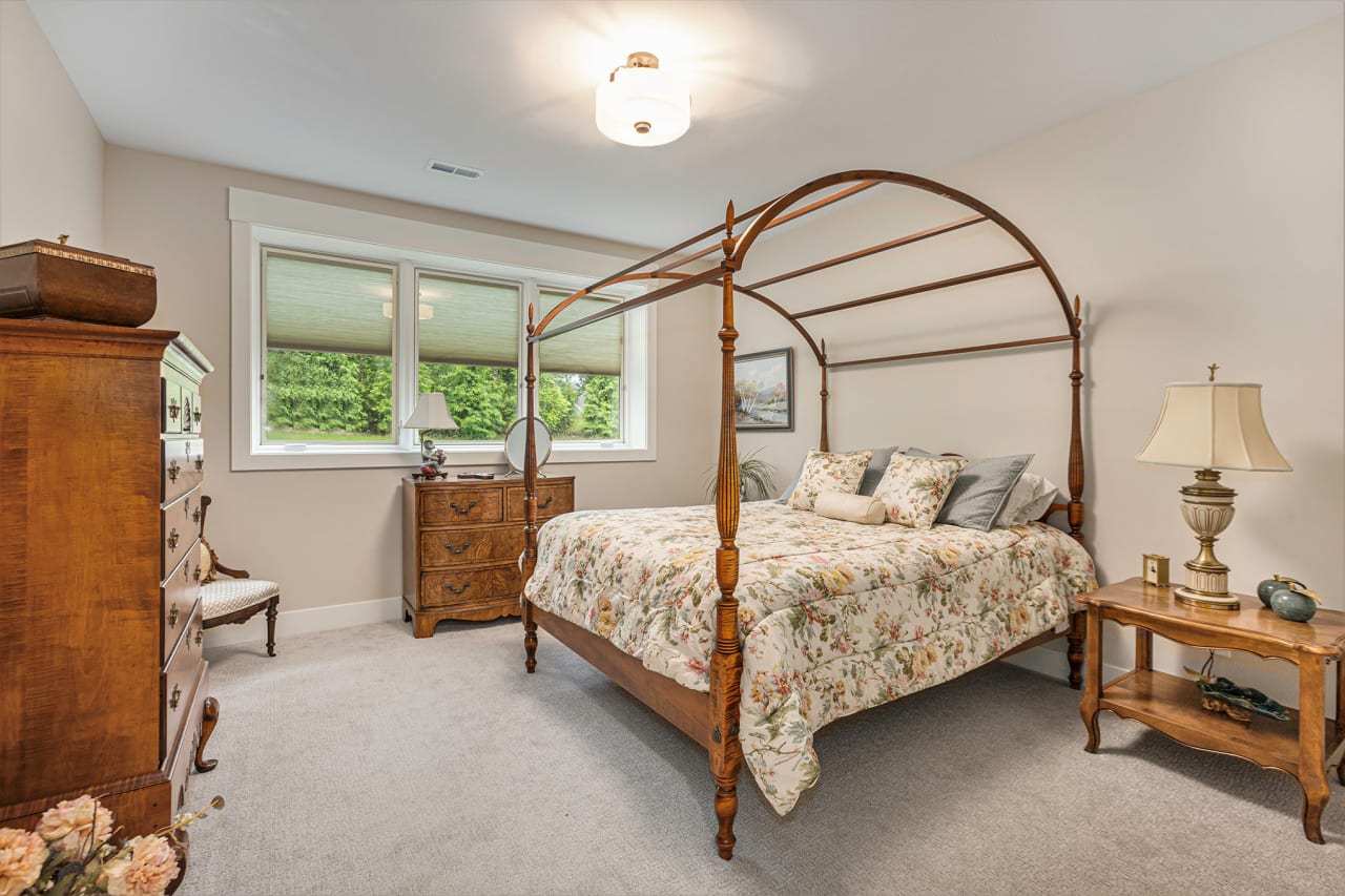 A bedroom with a canopy bed, dresser, and nightstand