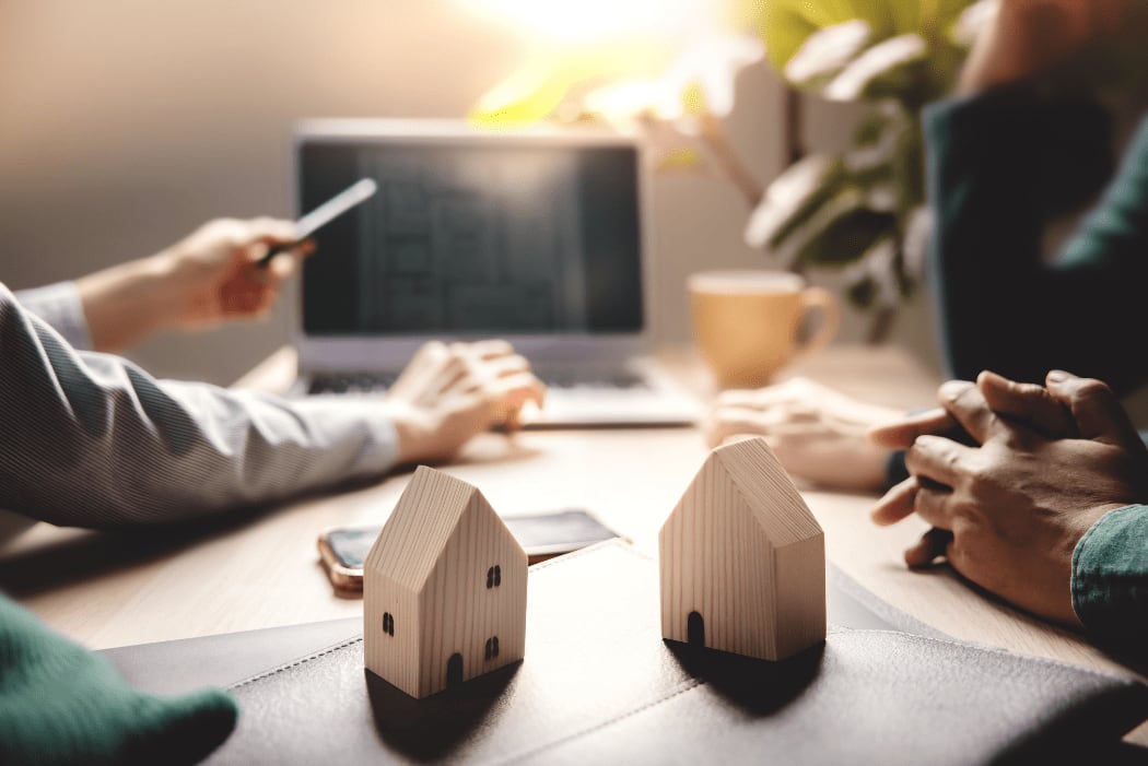 a real estate presentation with small wood block houses on the table