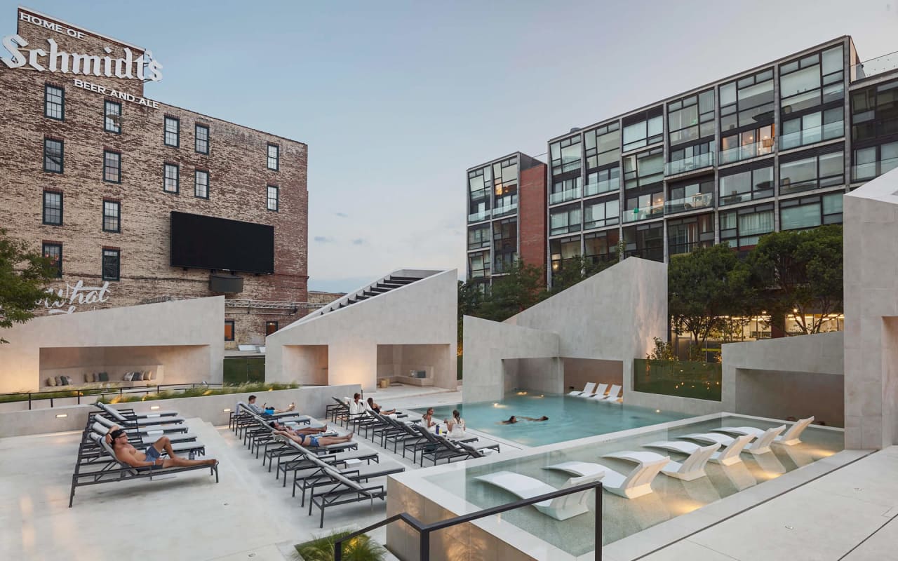 An aerial view of a modern, luxurious rooftop pool area with lounge chairs and cabanas.