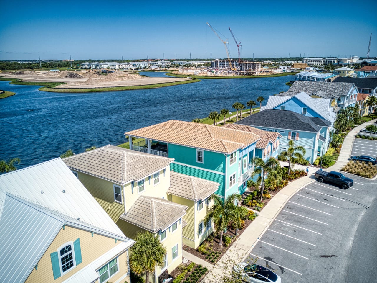 A row of colorful houses in a variety of shapes and sizes line the shore of a lake.