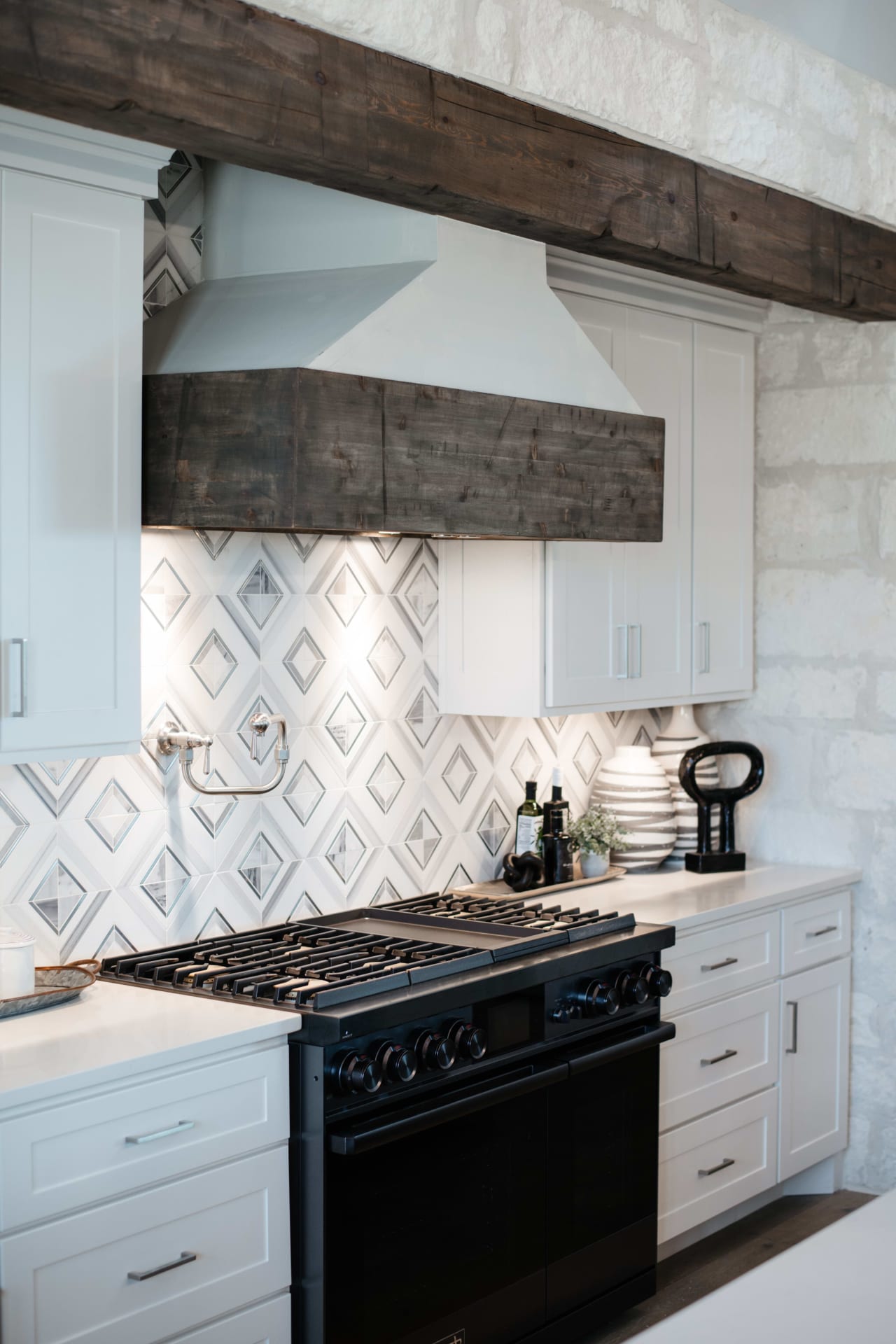 A kitchen with a black stovetop oven and white cabinets.