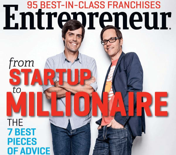  The cover of "Entrepreneur" magazine features two smiling men standing side-by-side against a white background. 