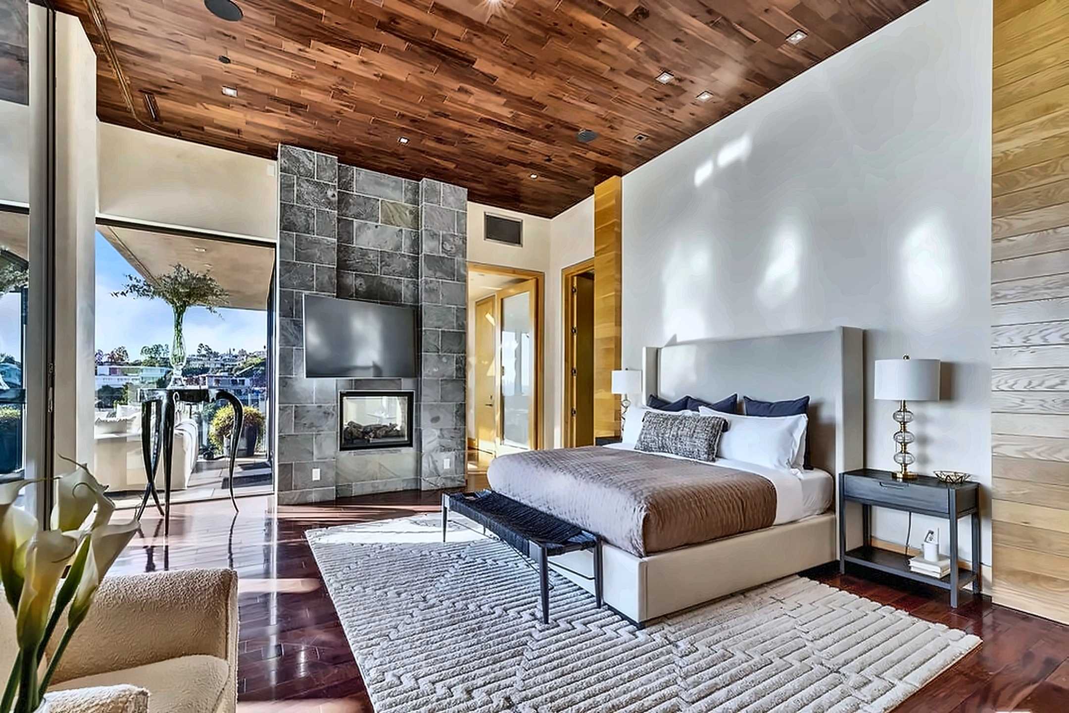Primary bedroom opening to a balcony with hillside outlook