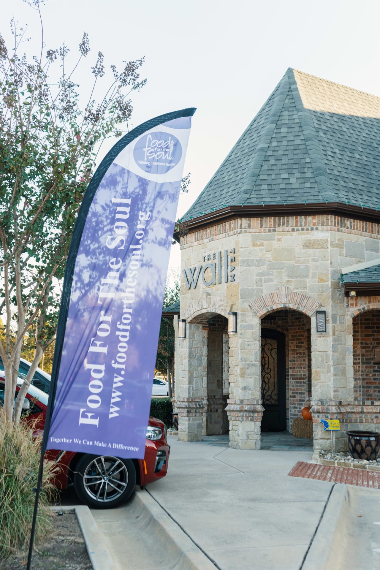 A car parked in front of a brick building with a purple flag