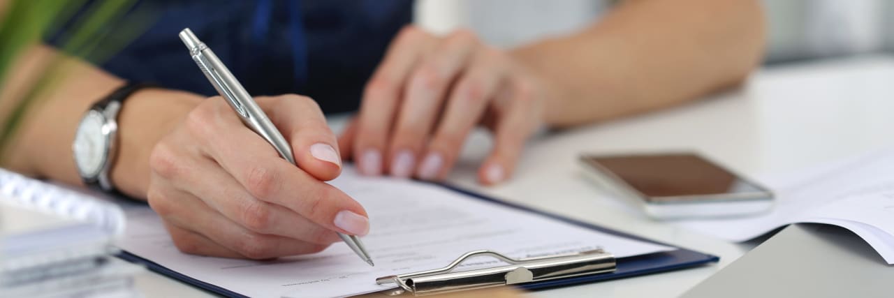 A person holding a pen to sign a contract.