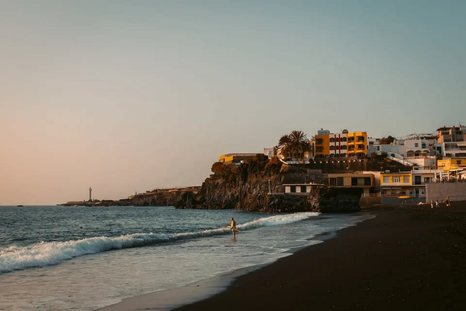 Coastal town with colorful buildings on a cliff overlooking the sea at sunset.