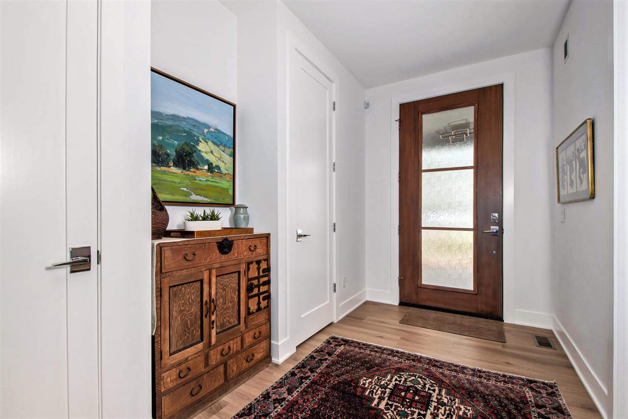 A hallway with a wooden cabinet and a rug