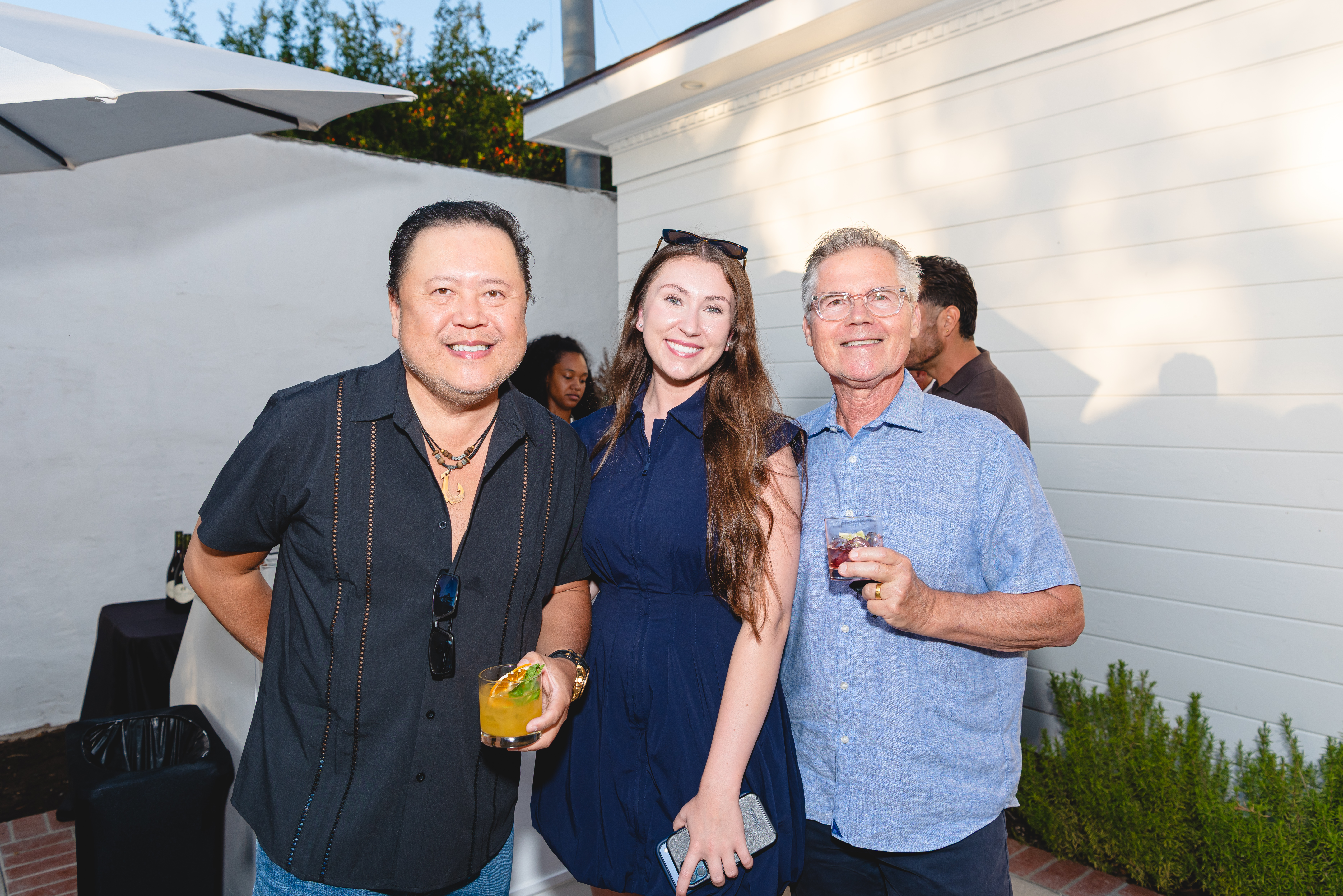 Three guests smiling with cocktails on the patio