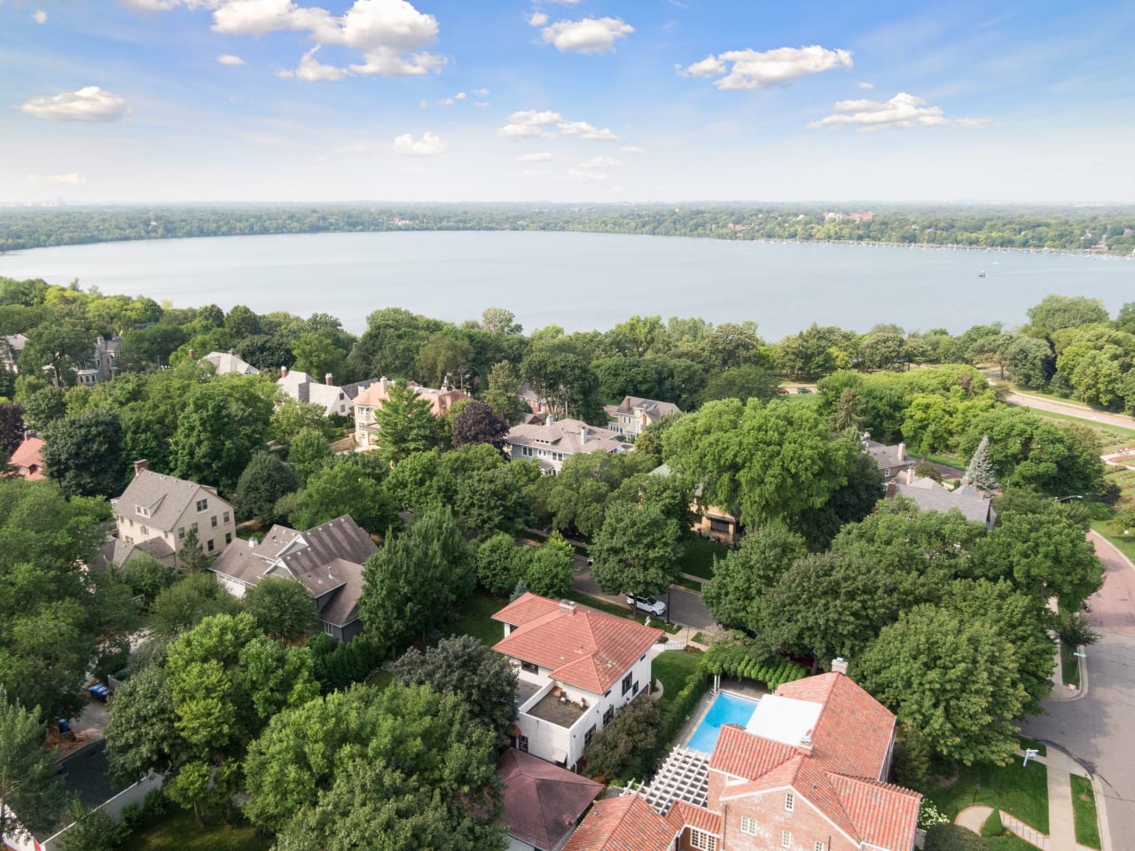 An aerial view of a suburban neighborhood with houses in various shapes and sizes and a lake in the background.