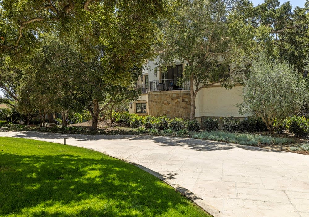 A stone structure with a fireplace, surrounded by outdoor furniture, a pond, and lush greenery