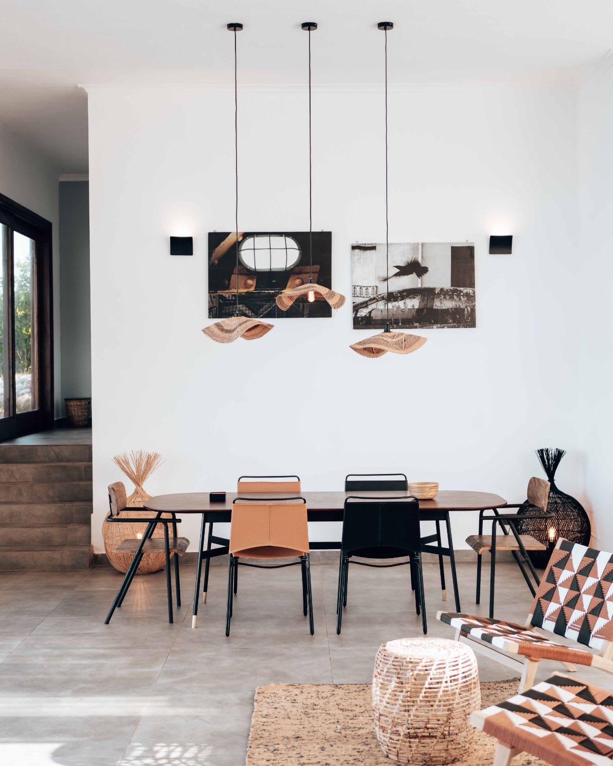 A dining room with a wooden table, leather chairs, and pendant lights.