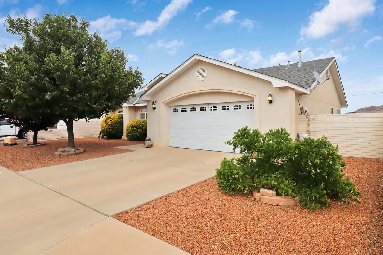 A white house with a garage door and a driveway.