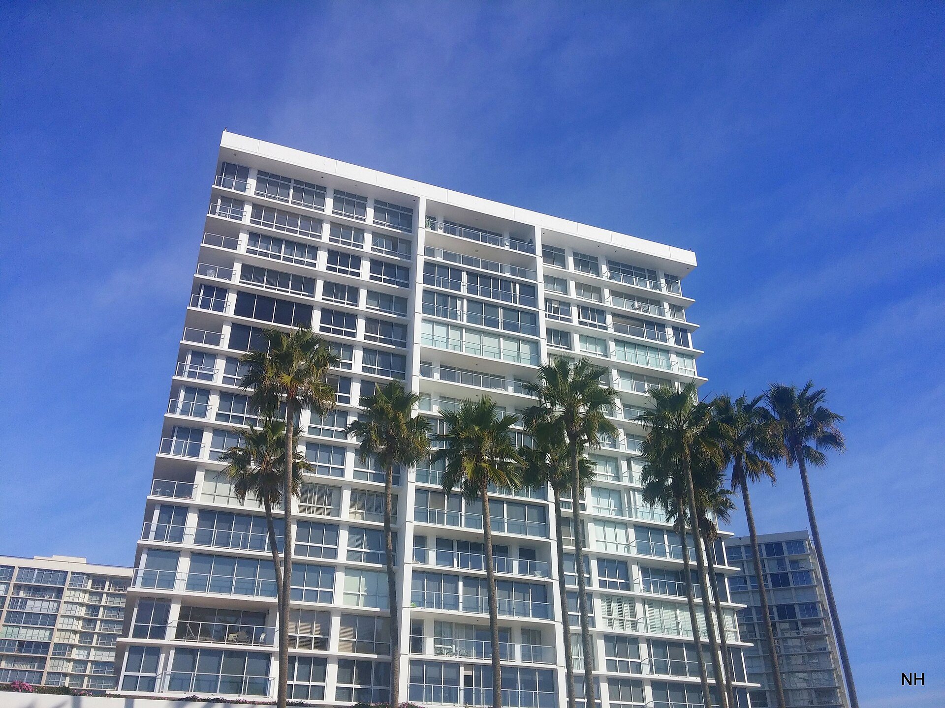 Coronado Shores condominium tower with balconies and palms under a blue sky