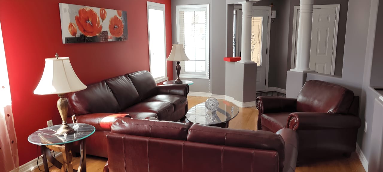 A red living room with two red leather couches, a red chair, and a glass coffee table.