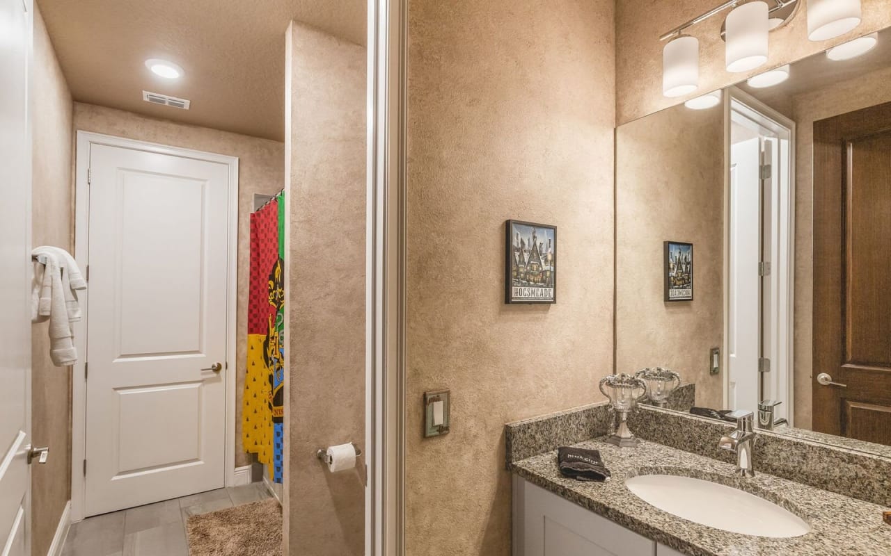 A clean and tidy bathroom with a marble countertop, a large mirror, and a sink with a single faucet.