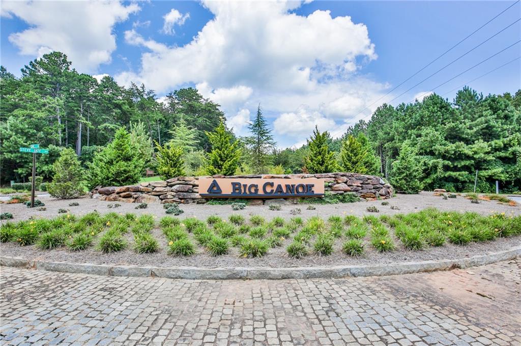 Stone wall with a sign that reads "Big Canoe" in the center of a grassy area.