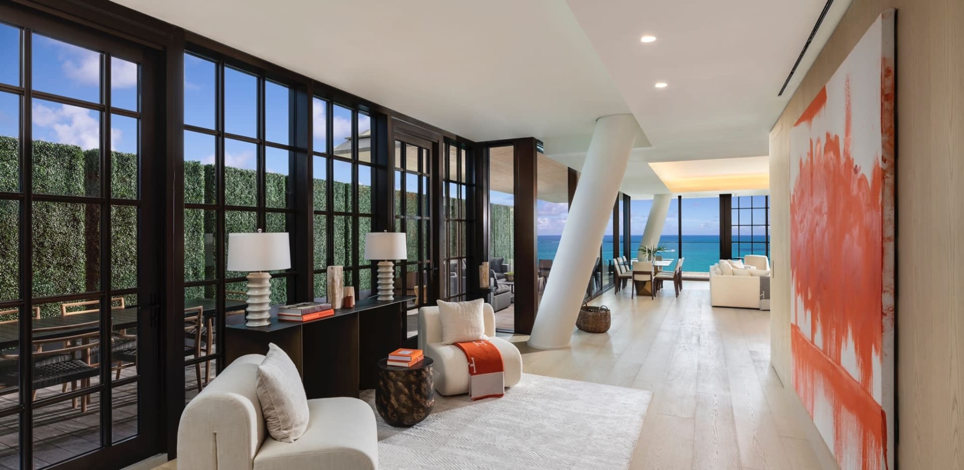 Modern living room with glass doors, white seating, and an ocean view.