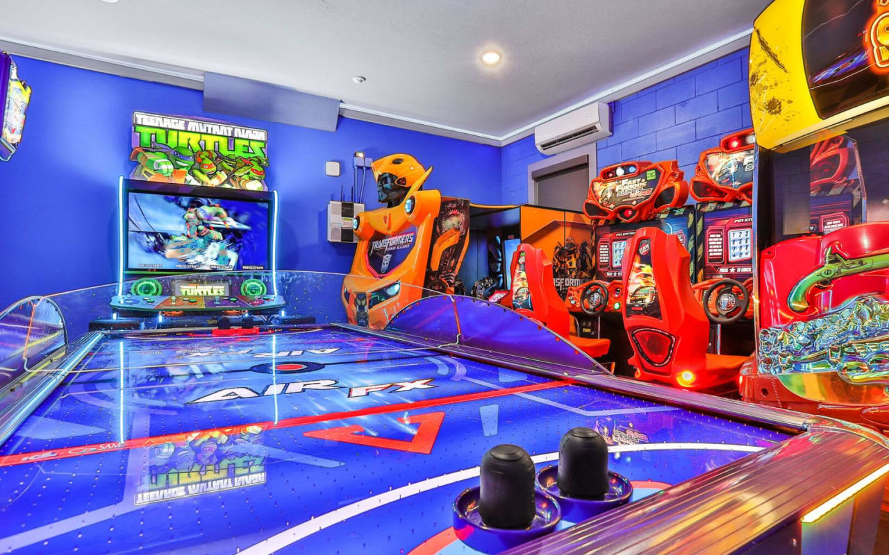 A game room with arcade games and an air hockey table.