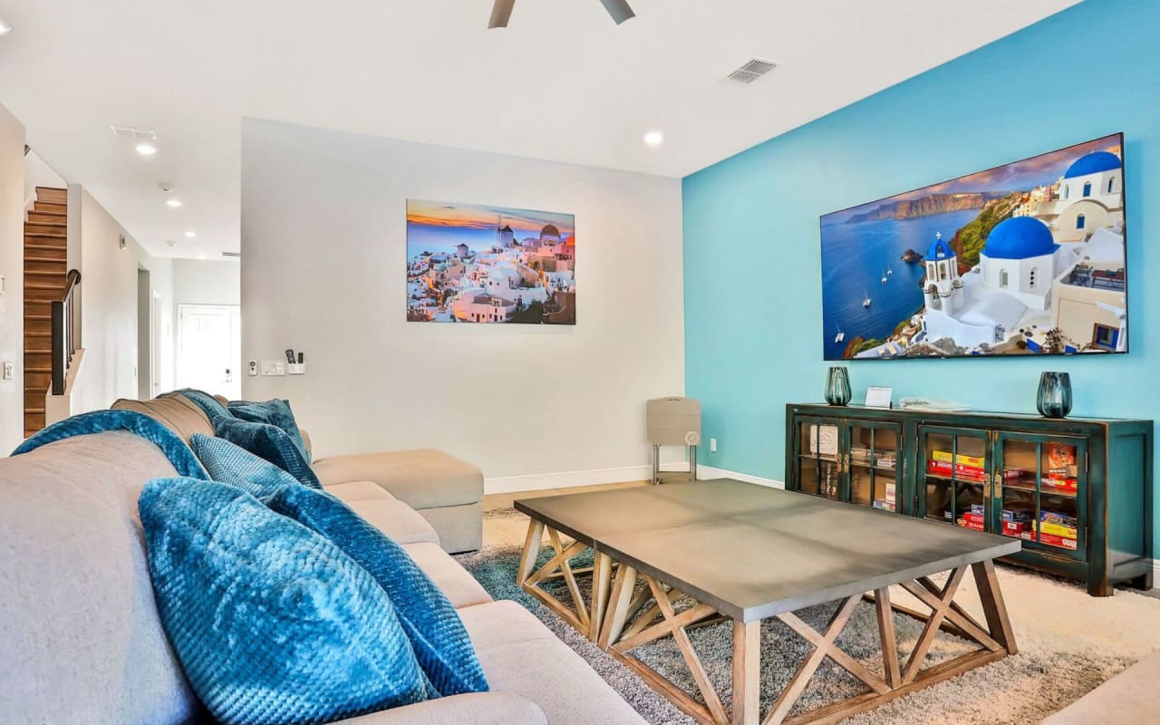 A living room interior with a couch, coffee table, and flat screen television mounted on the wall.