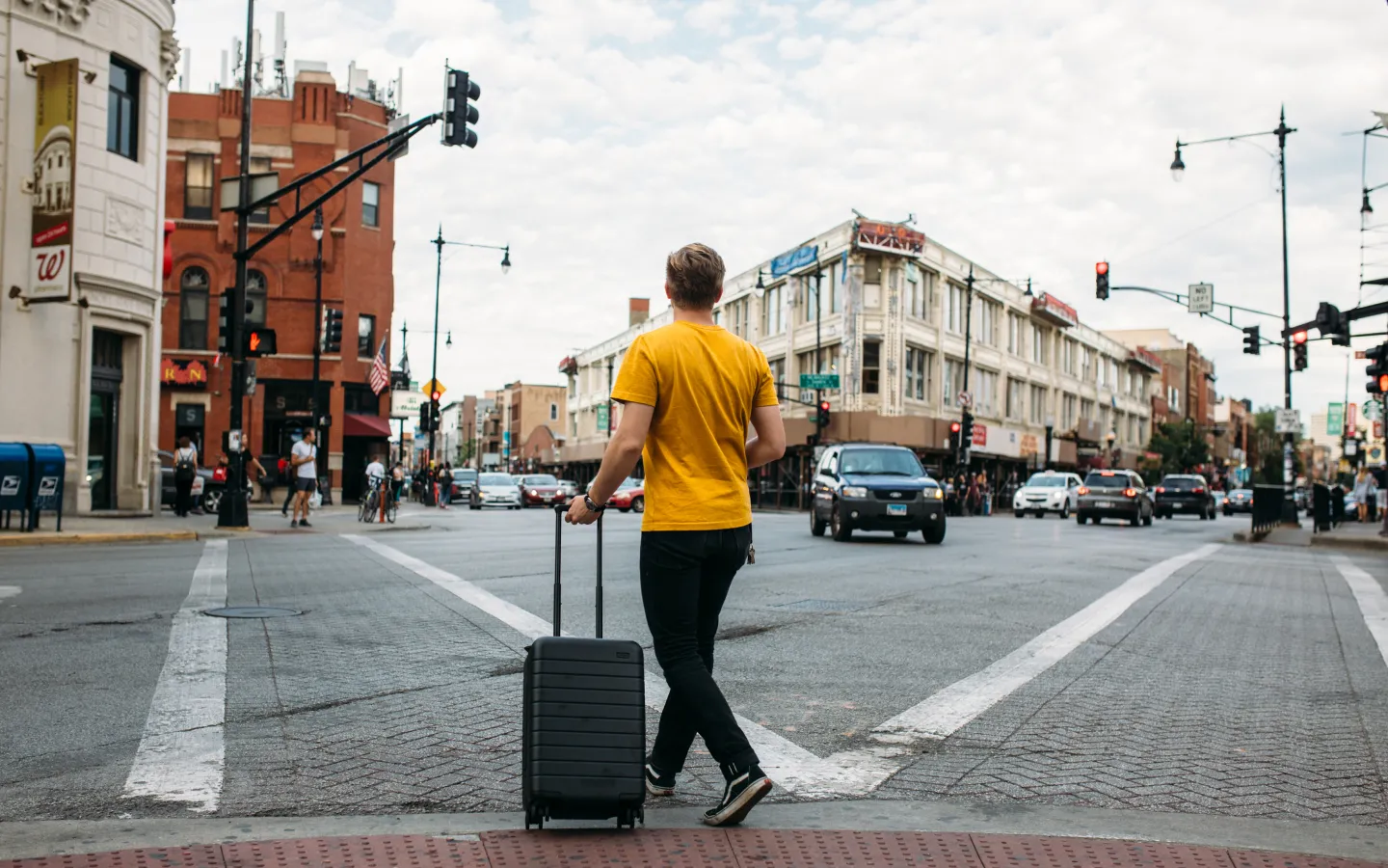 Person walking through city crosswalk with luggage