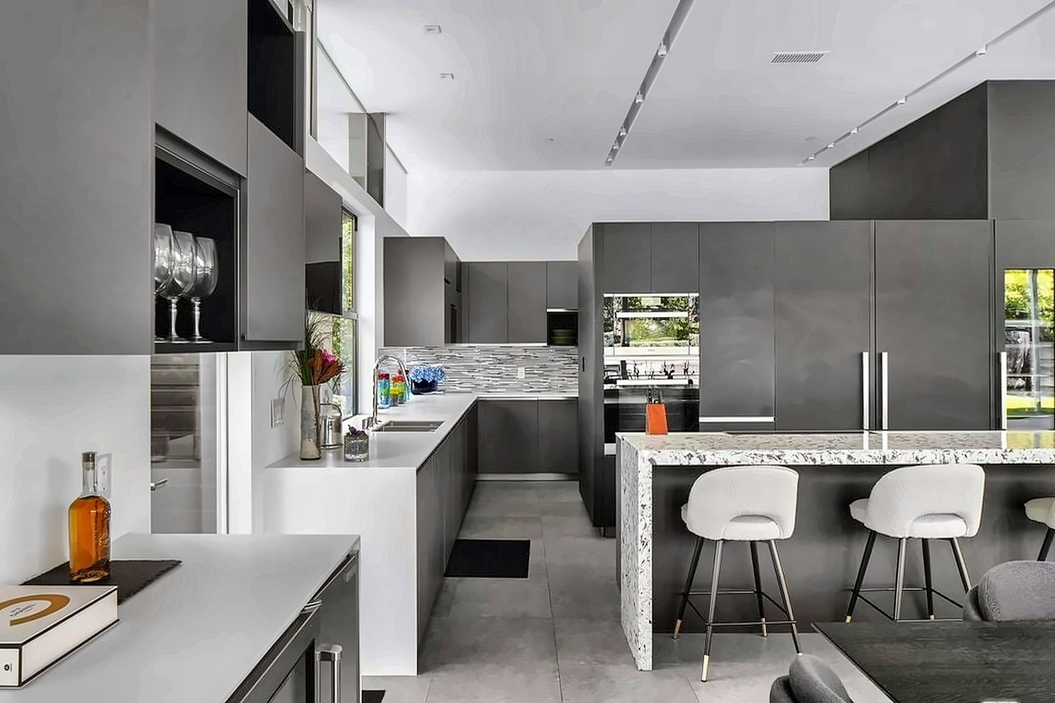 Modern Beverly Hills kitchen with custom gray cabinetry, integrated appliances and a stone waterfall island