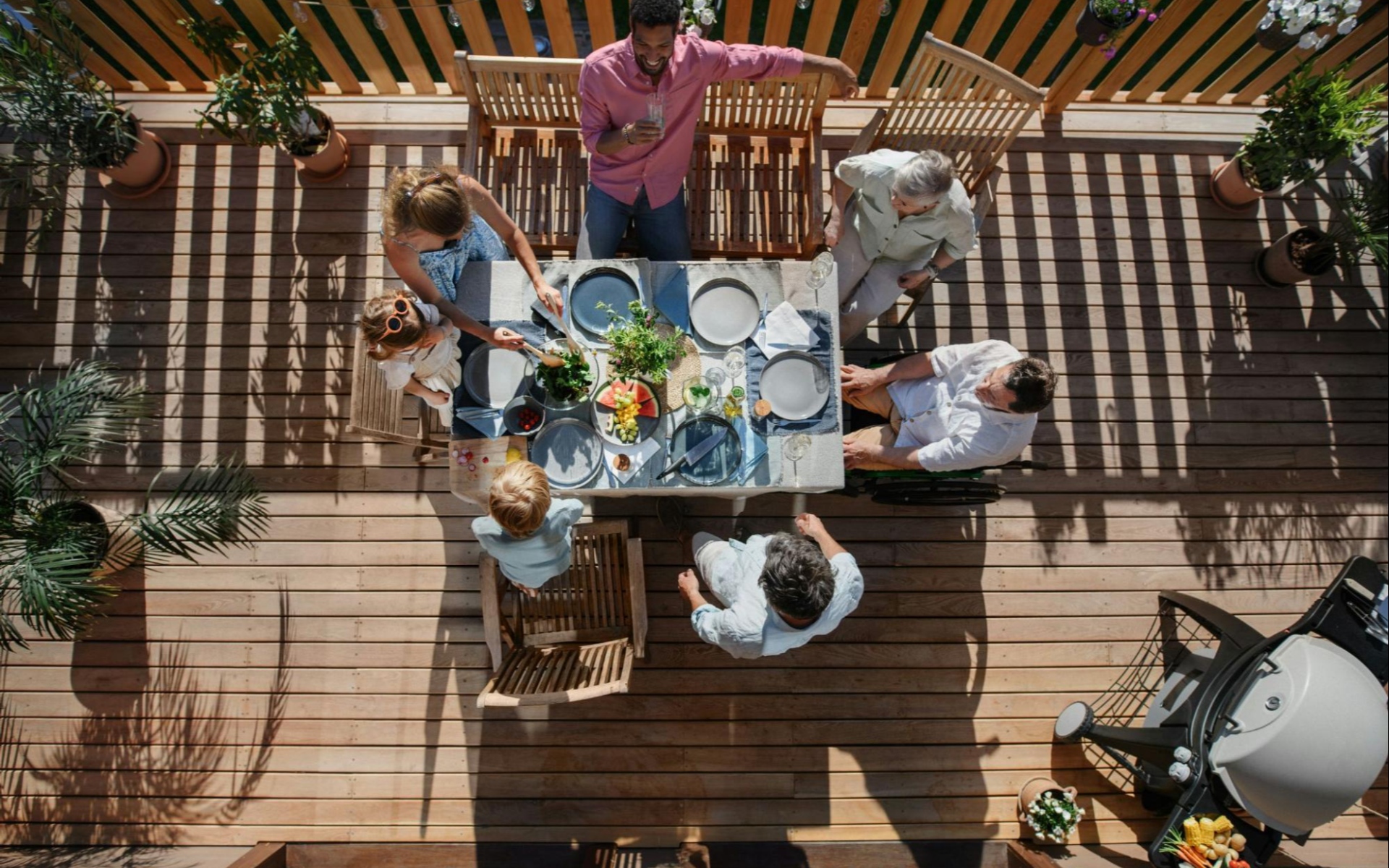 People Enjoying Outdoor Dinner Party on Wooden Deck at Real Estate Property