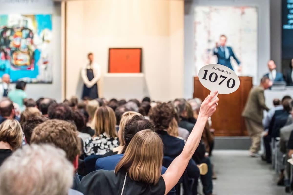 A bidder raises a Sotheby's paddle marked 1070 in a crowded auction room.