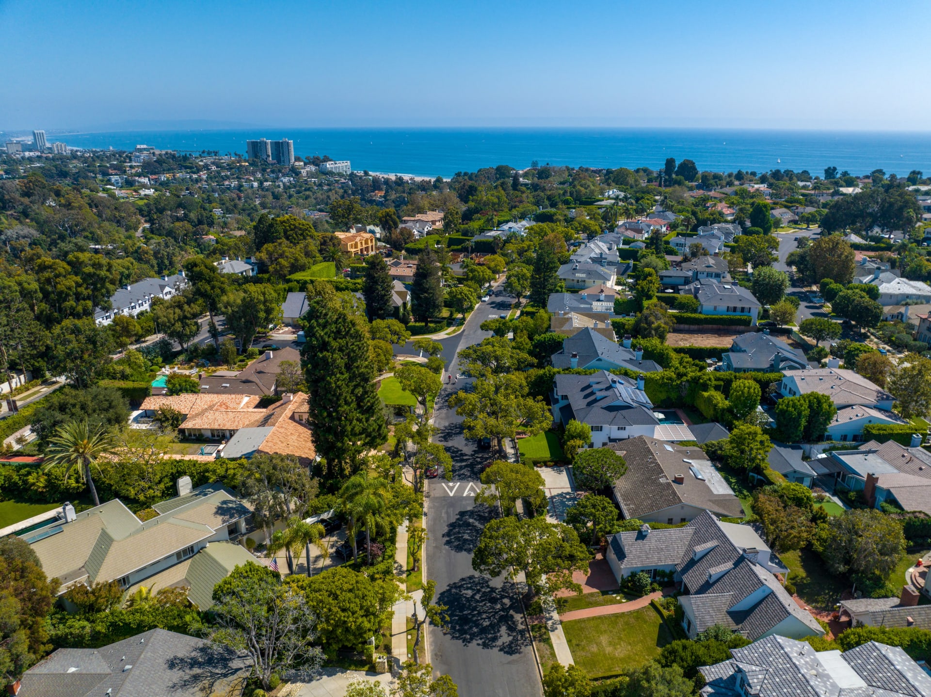  An aerial view captures a sprawling residential neighborhood with a clear blue ocean coastline in the background 