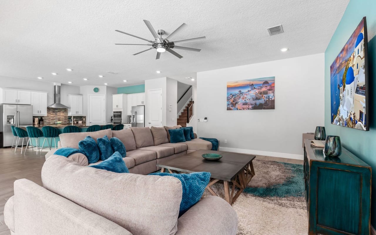 A living room with a comfortable couch, coffee table, and ceiling fan.